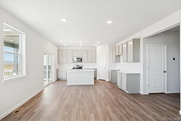 a large white kitchen with a refrigerator a sink dishwasher a stove and white cabinets with wooden floor