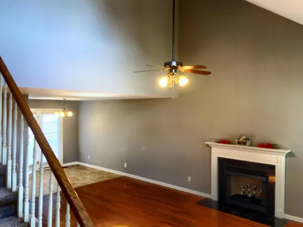 a view of an empty room with wooden floor fan and a fireplace