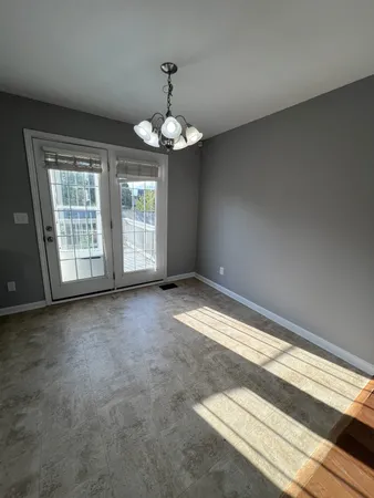 an empty room with chandelier fan and windows
