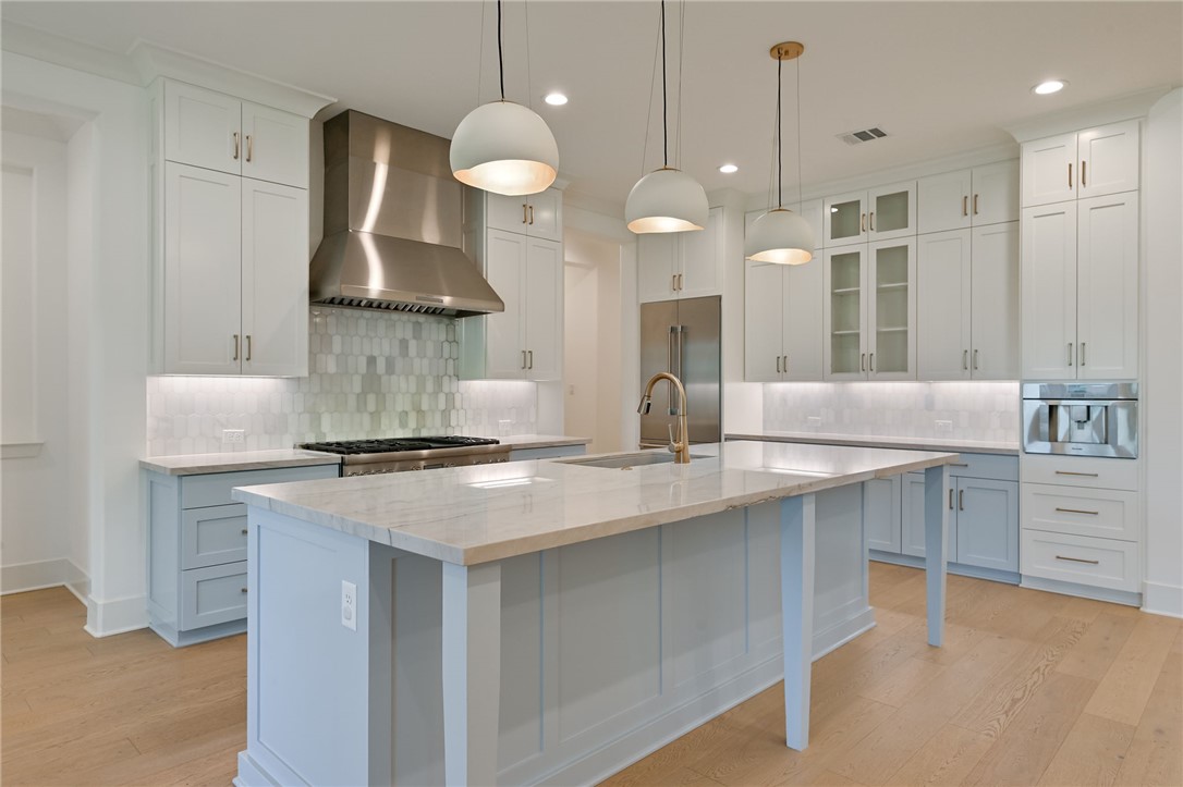 5115 Inverness Drive Bryan, TX 77802 - Photo 7 of 28 Kitchen featuring a large central island with a light blue finish, light wood-finish flooring, white upper cabinetry, light blue lower cabinetry, and stainless steel appliances