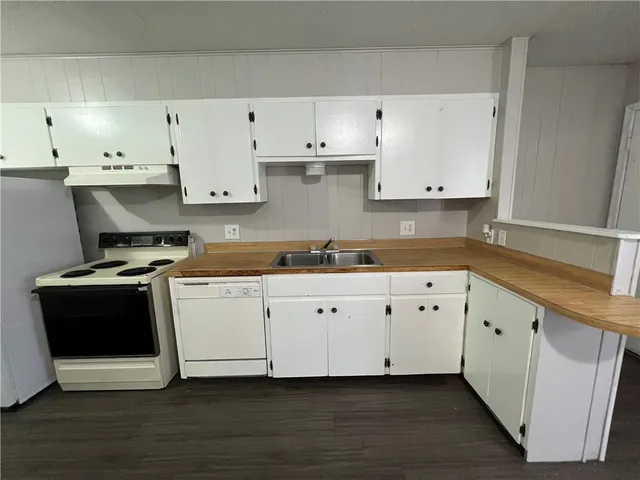 a white kitchen with granite countertop stainless steel appliances and wooden cabinets