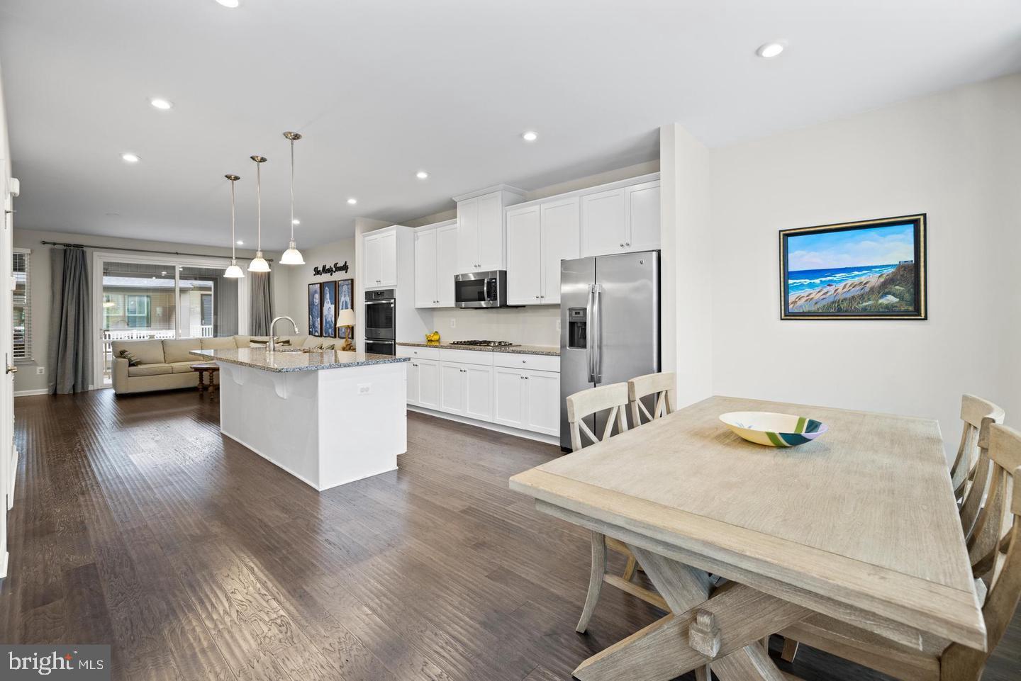 22255 Sims Terrace Ashburn, VA 20148 - Photo 11 of 27 a kitchen with stainless steel appliances wooden floor dining table and chairs