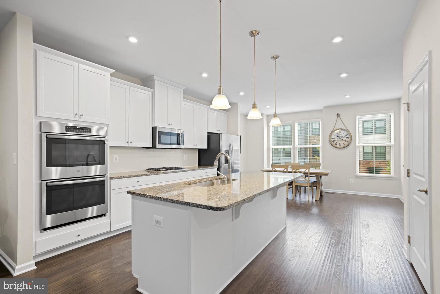 22255 Sims Terrace Ashburn, VA 20148 - Photo 15 of 27 a kitchen with stainless steel appliances granite countertop a stove top oven a sink dishwasher a dining table and chairs with wooden floor