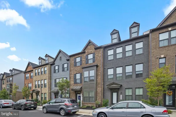 a front view of a building with lot of cars and trees
