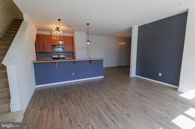 a view of a living room with kitchen furniture and wooden floor