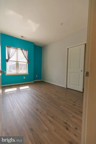 an empty room with wooden floor cabinet and windows