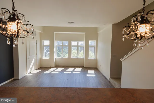 an empty room with wooden floor and kitchen view