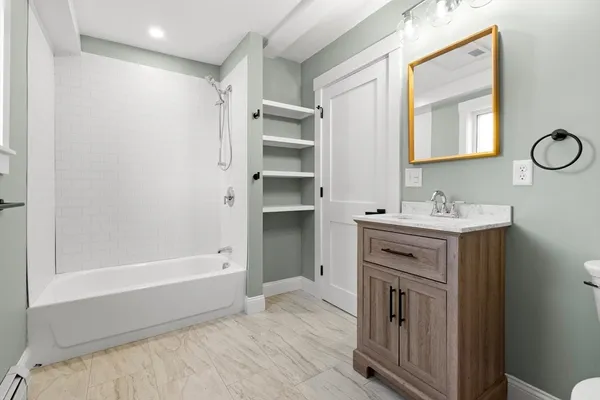 a bathroom with a tub sink and mirror