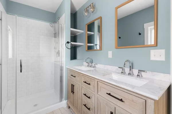 a bathroom with a granite countertop sink a mirror and shower