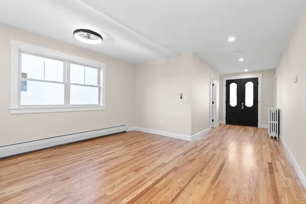 a view of an empty room with wooden floor and a window
