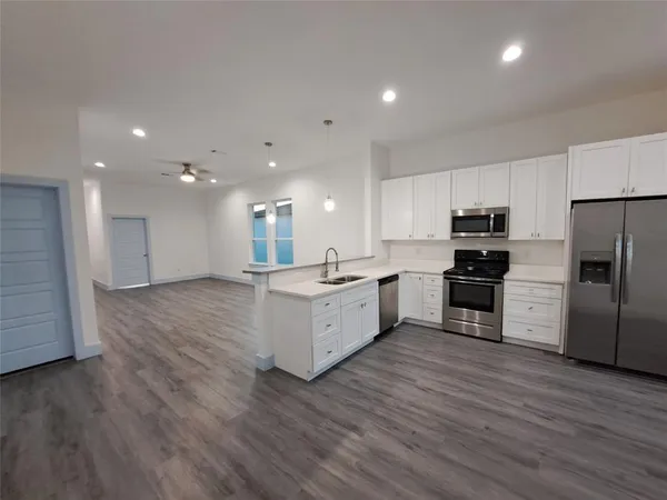a large kitchen with a center island wooden floor stainless steel appliances and cabinets