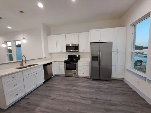 a large kitchen with a refrigerator a sink a stove top oven and cabinets