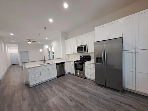 a large kitchen with a center island wooden floor stainless steel appliances and cabinets