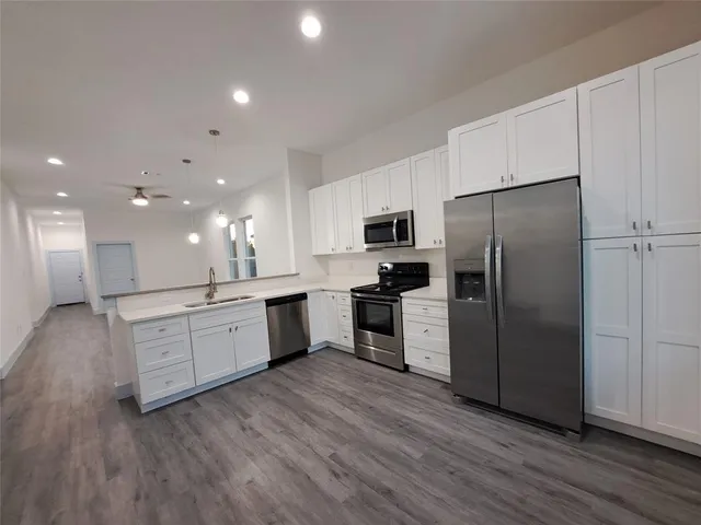a large kitchen with a center island wooden floor stainless steel appliances and cabinets
