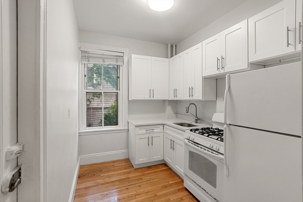 30 Kilsyth Road, Unit 3 Brookline, MA 02445 - Photo 4 of 11 a kitchen with granite countertop a refrigerator and white cabinets