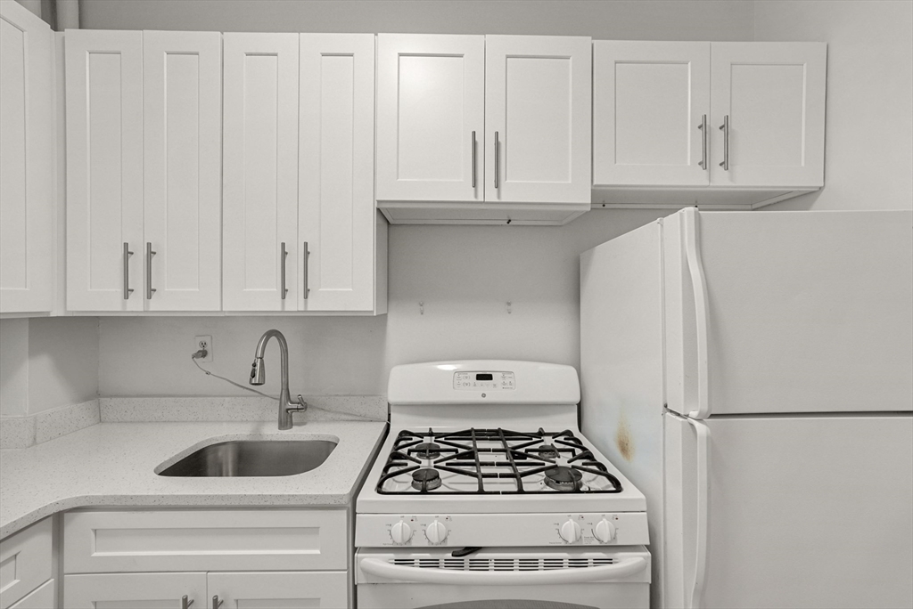 30 Kilsyth Road, Unit 3 Brookline, MA 02445 - Photo 5 of 11 a kitchen with white cabinets and white appliances