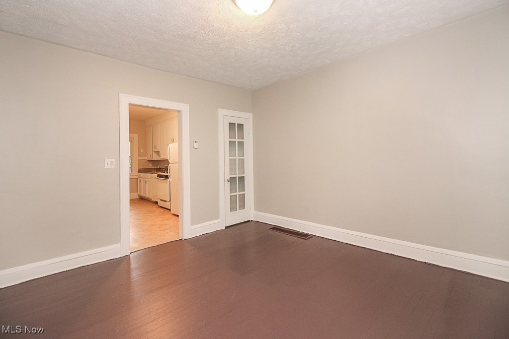 3085 Somerton Road Cleveland, OH 44118 - Photo 7 of 16 Empty room featuring visible vents, baseboards, dark wood-type flooring, and a textured ceiling