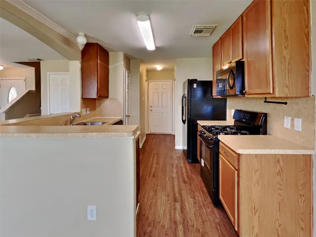 a kitchen with stainless steel appliances a refrigerator stove and wooden floor