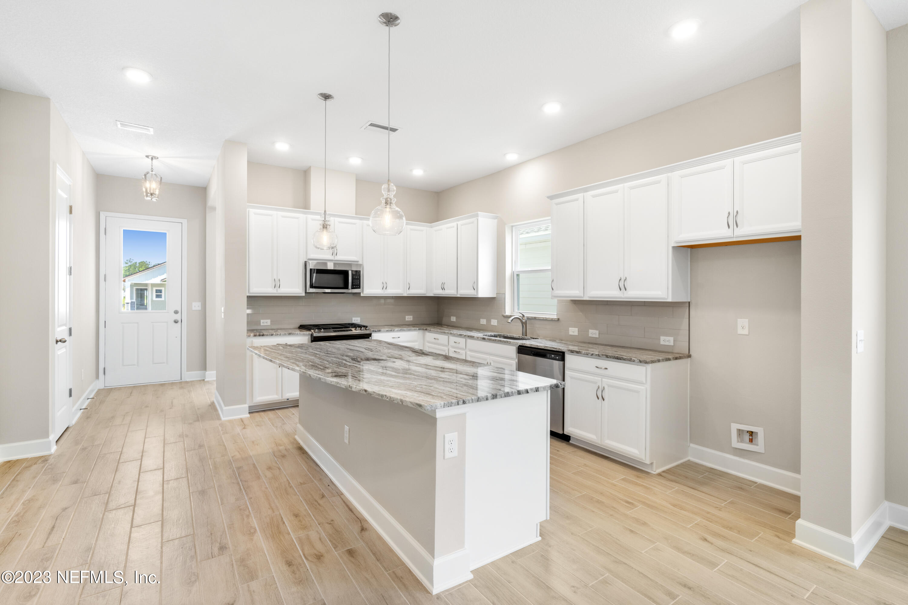 92 Alston Drive St. Augustine, FL 32092 - Photo 4 of 14 a large kitchen with kitchen island a stove a sink a refrigerator and white cabinets