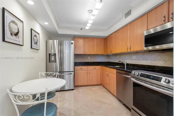 a kitchen with stainless steel appliances kitchen island granite countertop a refrigerator and a stove top oven