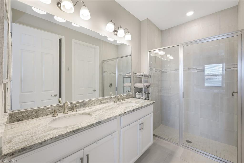 1114 Tranquil Brook Drive Naples, FL 34114 - Photo 16 of 32 a bathroom with a granite countertop sink a large mirror and a shower