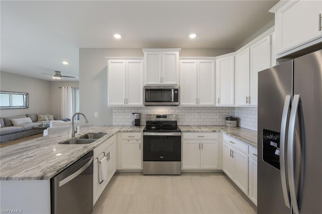 1114 Tranquil Brook Drive Naples, FL 34114 - Photo 7 of 32 a kitchen with a sink stainless steel appliances and white cabinets