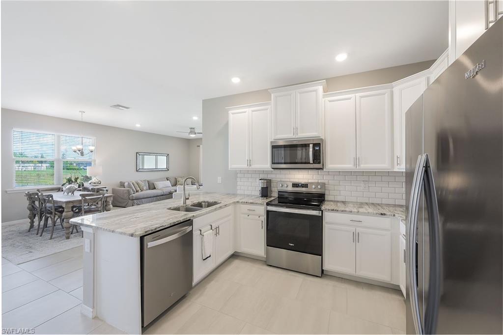 1114 Tranquil Brook Drive Naples, FL 34114 - Photo 8 of 32 a kitchen with stainless steel appliances granite countertop a stove top oven a sink a refrigerator and white cabinets