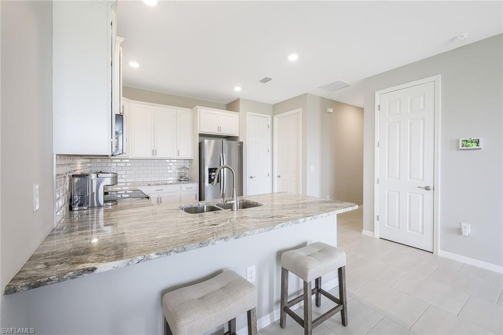 1114 Tranquil Brook Drive Naples, FL 34114 - Photo 9 of 32 a kitchen with kitchen island granite countertop a sink a stove and a refrigerator