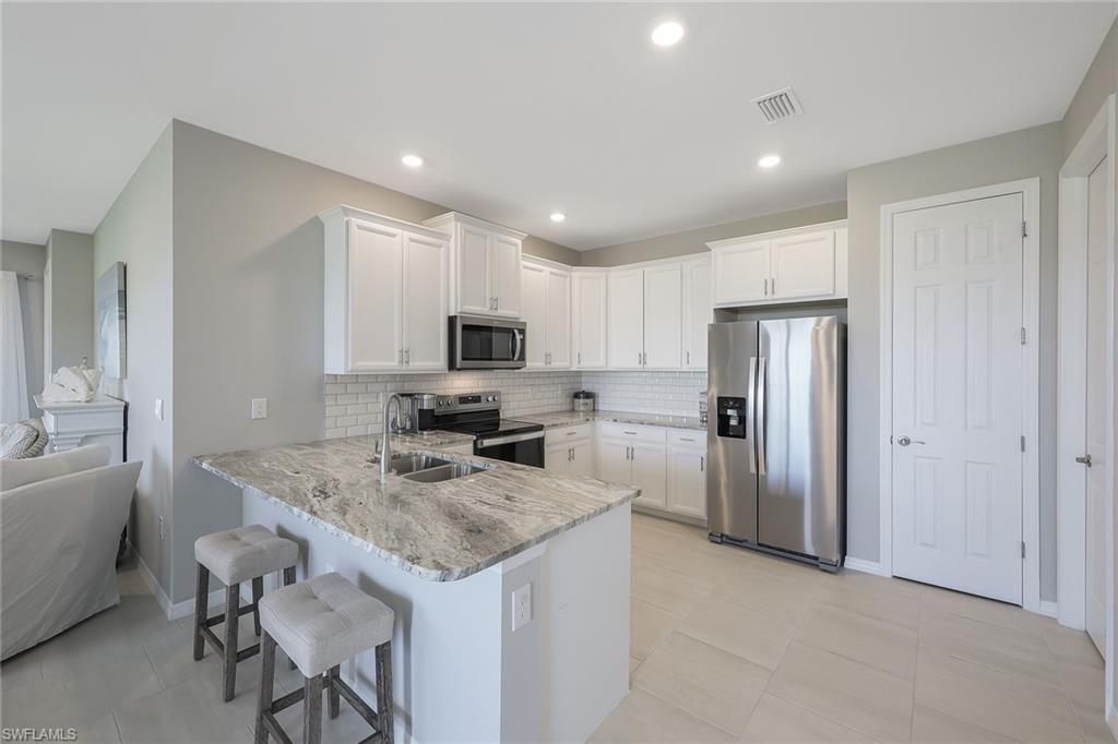 1114 Tranquil Brook Drive Naples, FL 34114 - Photo 10 of 32 a kitchen with stainless steel appliances granite countertop a sink refrigerator and microwave
