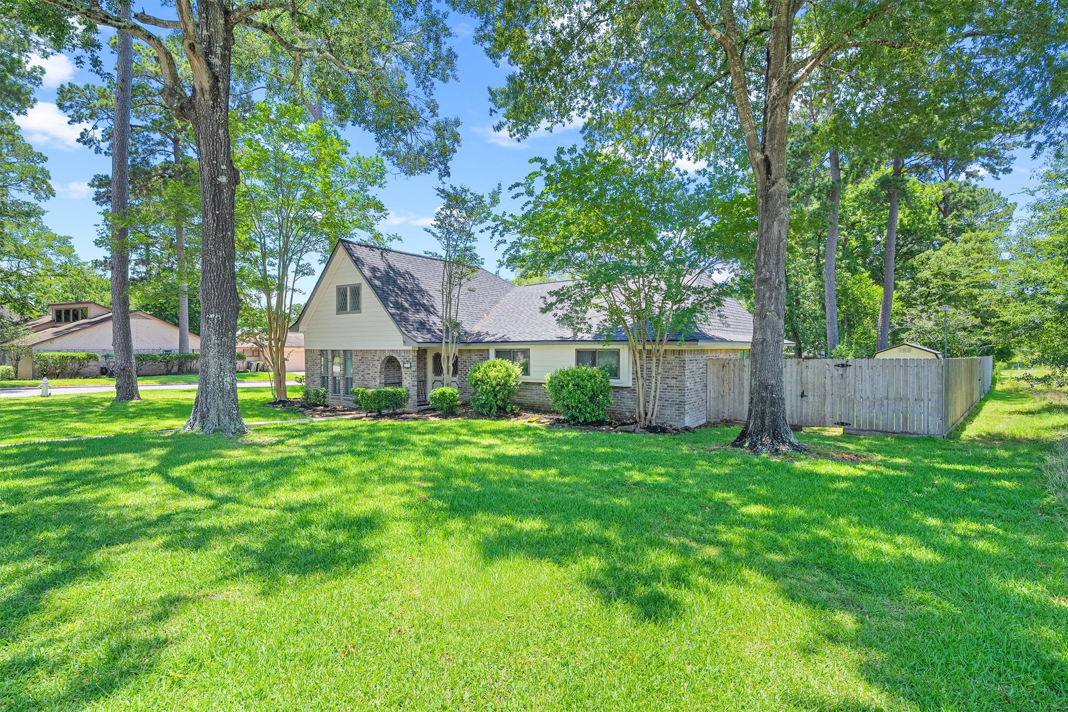 826 North Rivershire Drive Conroe, TX 77304 - Photo 38 of 46 From this angle the full footprint of the home comes into view. One story, brick exterior, mature trees framing the property, and that fully fenced backyard tucked just behind. This lot has presence from every direction.