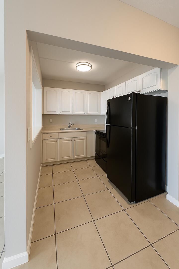 4670 Northeast 5th Avenue, Unit 15 Boca Raton, FL 33431 - Photo 6 of 9 a kitchen with a refrigerator and cabinets