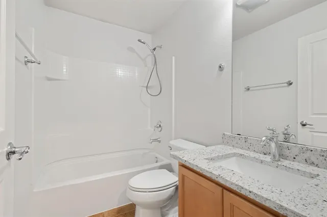 a bathroom with a granite countertop sink a toilet and shower