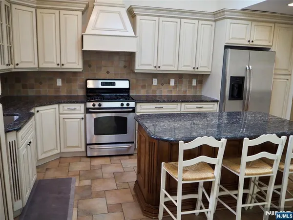 a kitchen with granite countertop a stove a sink and a refrigerator