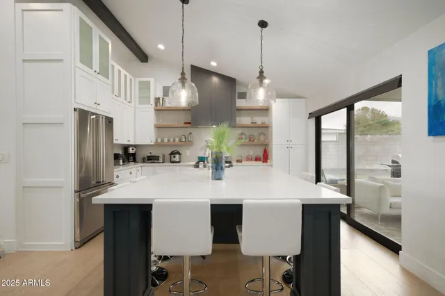 a large kitchen with stainless steel appliances kitchen island granite countertop a table chairs in it and wooden floors