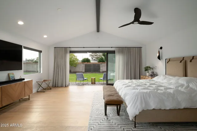 a bed room with a bed television and a large window