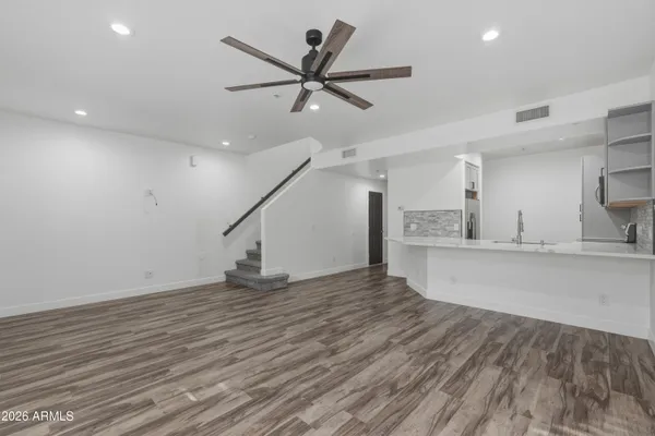 a view of kitchen and empty room with wooden floor