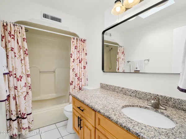 a bathroom with a granite countertop sink a mirror and shower