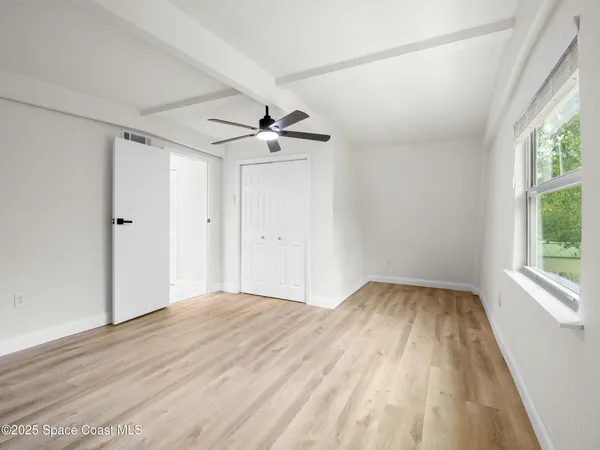 a view of empty room with window and wooden floor