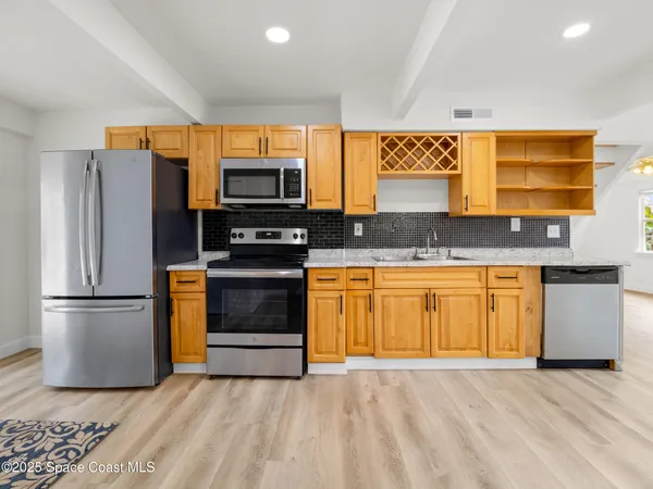 a kitchen with granite countertop a refrigerator and a stove top oven