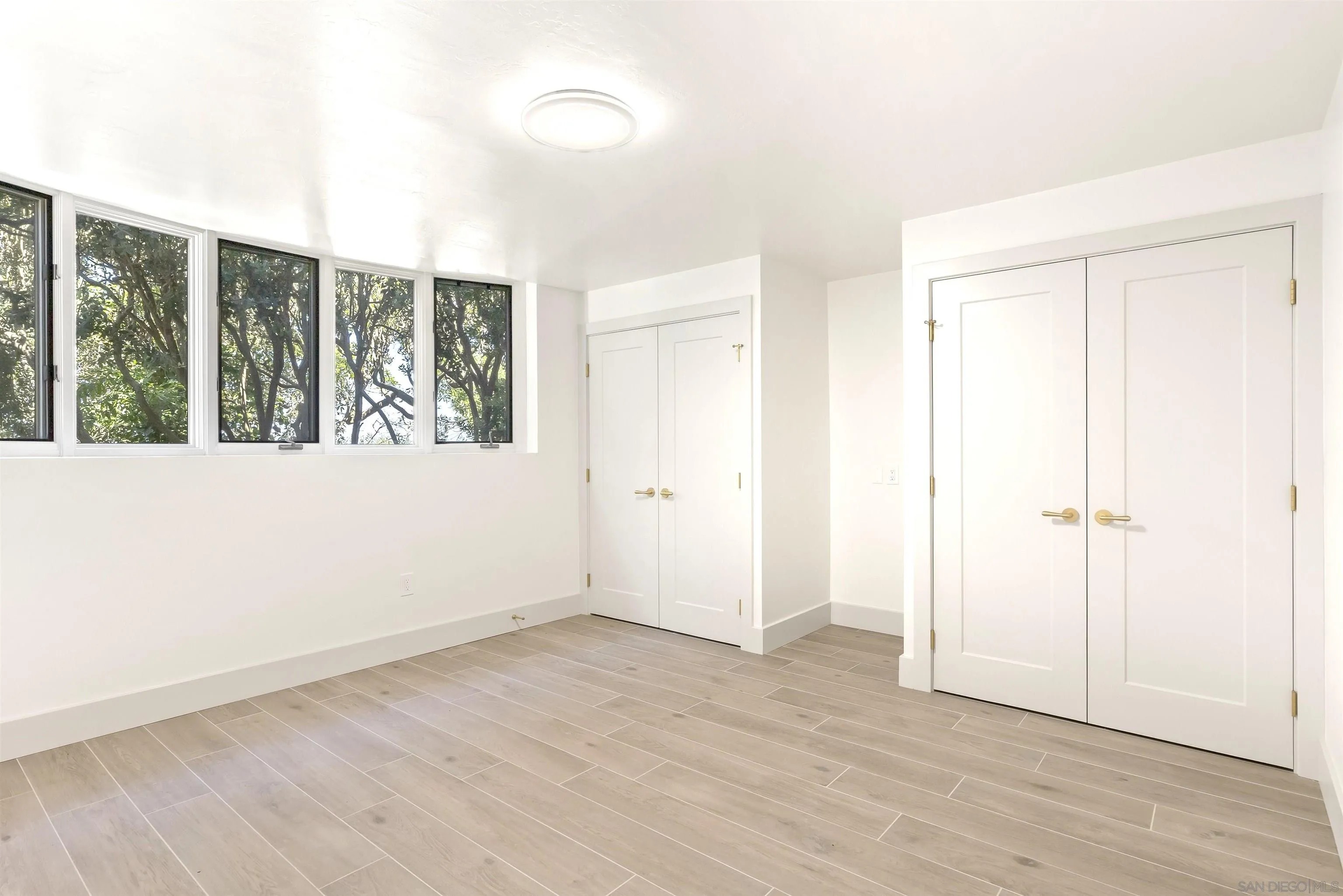 2302 Rue Adriane La Jolla, CA 92037 - Photo 29 of 31 an empty room with wooden floor and windows
