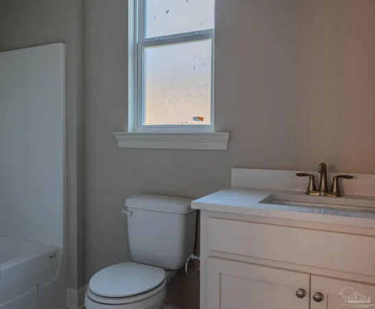 a bathroom with a toilet sink vanity and mirror