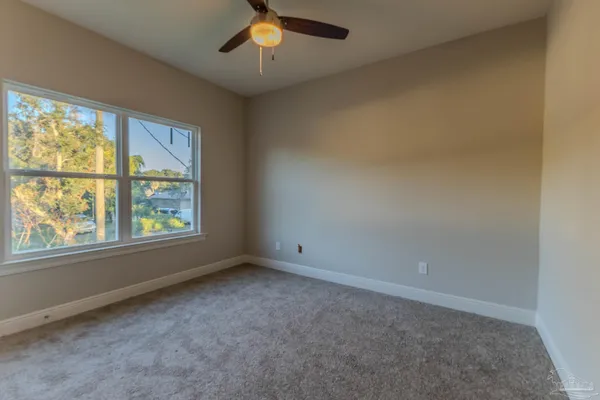 an empty room with windows closet and chandelier fan
