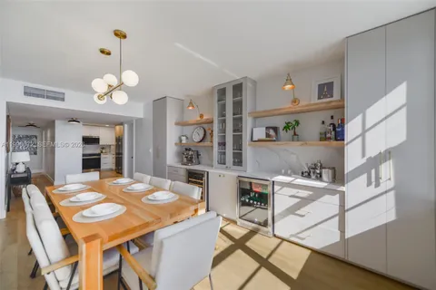 a dining room with stainless steel appliances furniture a fireplace a chandelier and a mirror