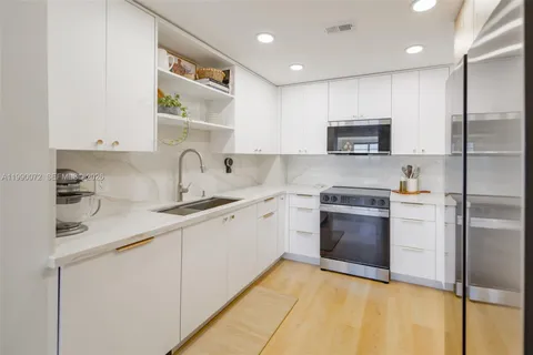 a kitchen with stainless steel appliances granite countertop a refrigerator a stove and a sink