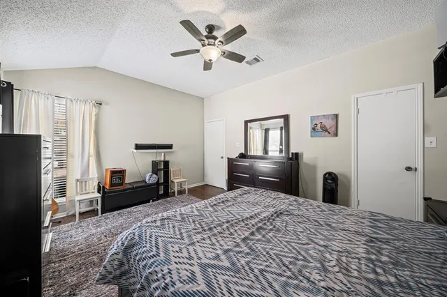 a bedroom with a bed dresser and a flat tv screen