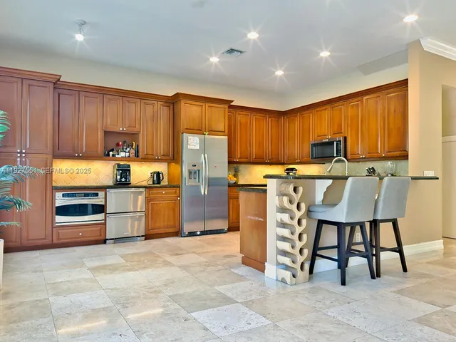 a kitchen with granite countertop a refrigerator cabinets and chairs