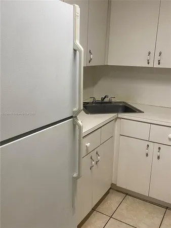 a kitchen with a refrigerator and white cabinets