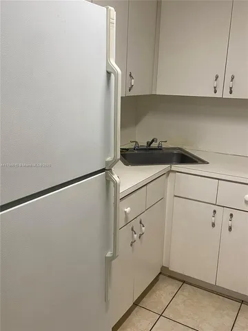 a kitchen with a refrigerator and white cabinets