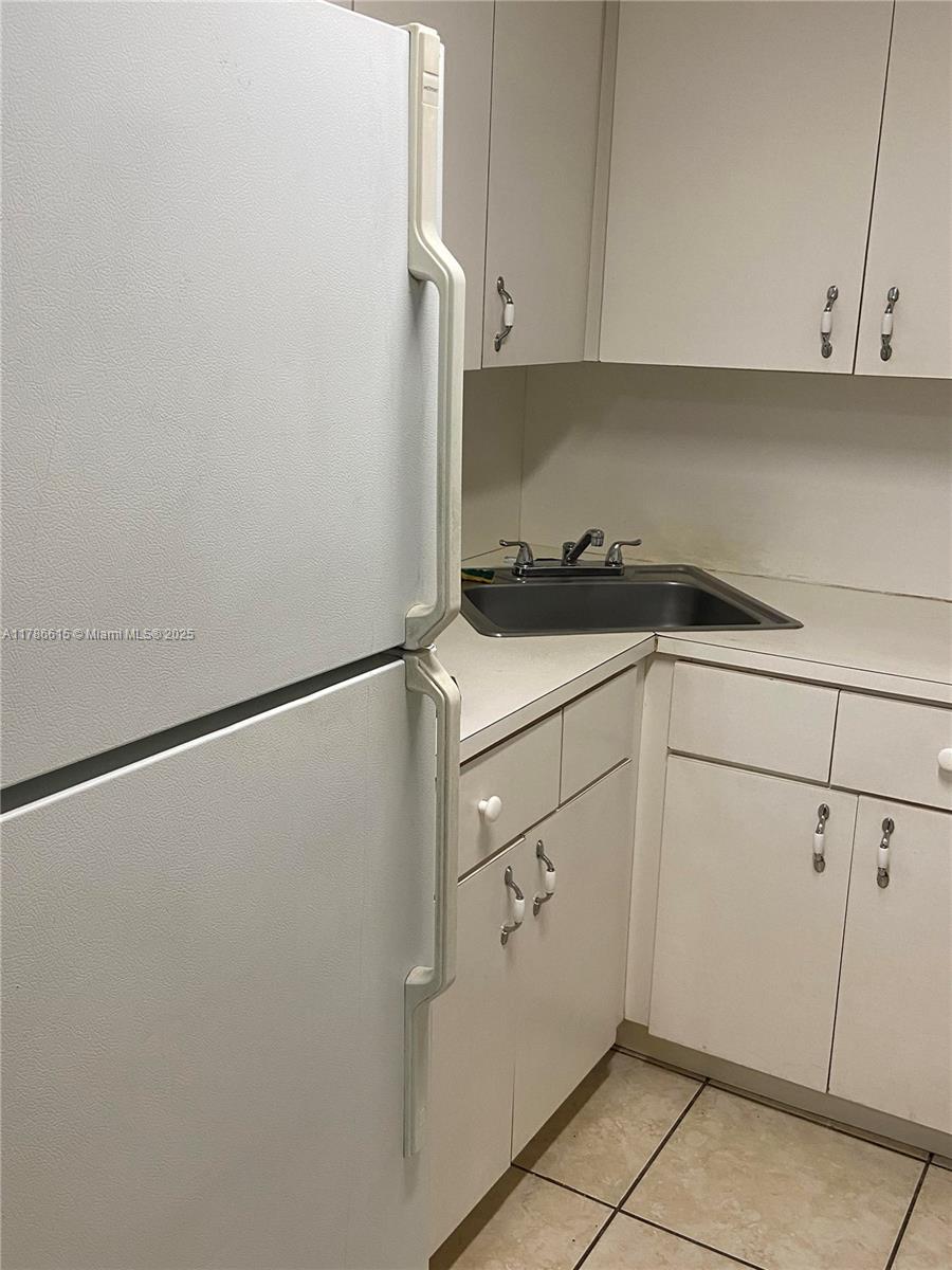 666 West 81st Street, Unit 127 Hialeah, FL 33014 - Photo 4 of 10 a kitchen with a refrigerator and white cabinets