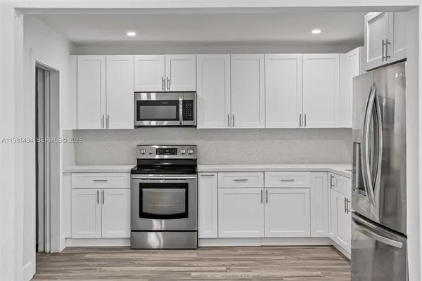 a kitchen with a refrigerator a sink and dishwasher with wooden floor